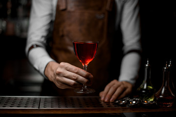 Professional bartender serving a red alcoholic cocktail in the glass