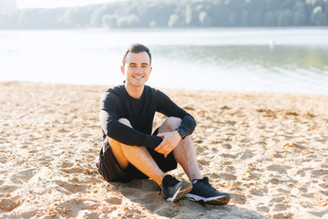 Photo of siling young guy, sitting on hte bach and relaxing after run