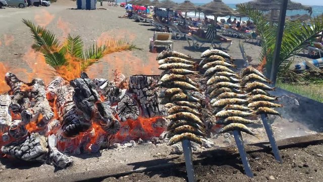 Sardines on sticks on fire are fried in a boat. Typical "espetos" food of Spain, Costa del Sol, Malaga. Traditional food.
