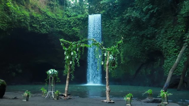 Timbumana Waterfall In A Secluded Jungle With A Perfect Bridal Veil Into A Pool in Ubud, Bali, Indonesia - With Wedding Arch or Arbor in Slow Motion