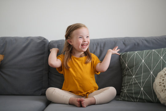 Caucasian girl child with Down syndrome on sofa