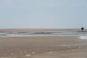 Meer mit Sandstrand und Spaziergänger am Horizont