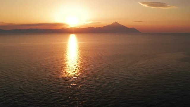 Aerial view of a slide from the drone on the panorama of the sea surface and the silhouette of Mount Athos, Greece in the bright light of the sunrise in the early morning. Holy Mount Athos in Greece