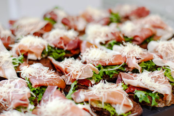 Snack plate at the event: prosciutto sandwiches, sun-dried tomatoes, fresh lettuce and grated cheese.