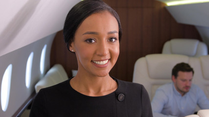 Businesswoman in private jet. Well dressed, confident female biracial entrepreneur smiling inside of business airplane cabin.