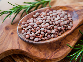 Whole Brown Lentils -  Masoor Dal on the wooden spoon, macro.