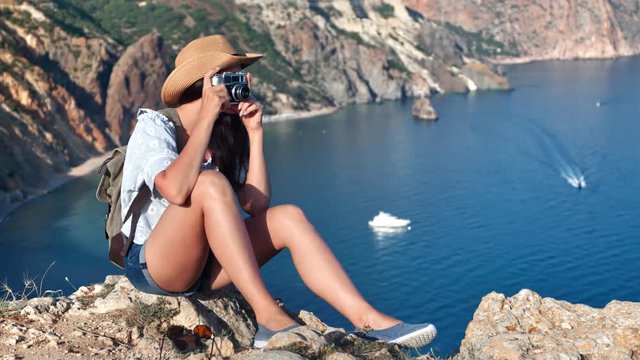 Carefree young travel woman having positive emotion taking picture using camera admiring sea landscape