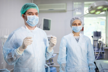 Medical assistant helps a surgeon.