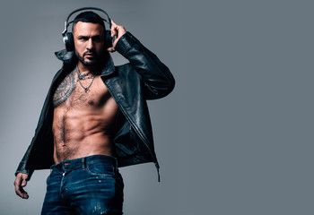 Music in headphones. Bearded hispanic man with muscular torso wearing headphones. Brutal latino man...