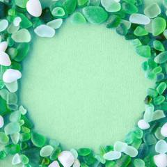 Close up of various sea glass pieces with empty circle shape in the middle on trendy neo mint...