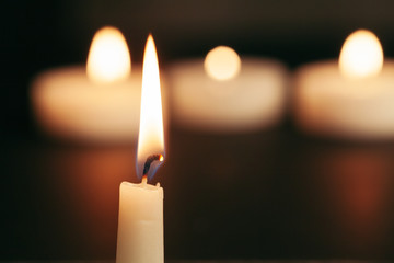 A single burning candle isolated with black background