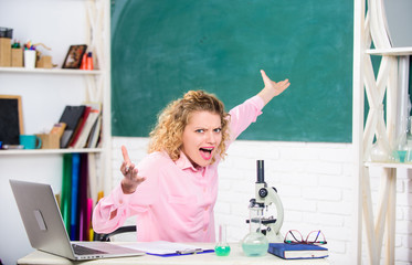 Woman tutor or student at desk with laptop and school equipment stationery. Emotional control. Emotional people concept. Emotional female teacher educator in classroom chalkboard background