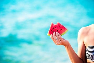 Fototapeta na wymiar Watermelon slice in woman hand over sea - POV. Summer beach concept. Tropical fruit diet.