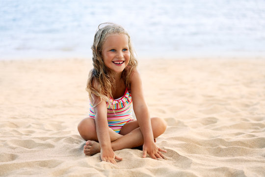 Adorable little girl relax on sandy beach in summer vacation