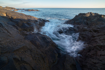 Waves braking on rocky shore of a sea