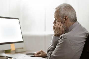 Senior man staring at the computer screen - obrazy, fototapety, plakaty