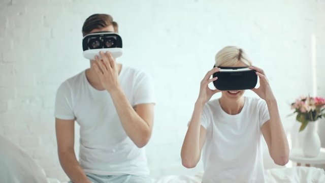 woman looking at man in Virtual reality headset and laughing at home