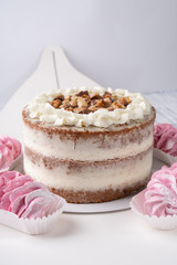 Chocolate puff cake with white cream and nuts on a white box with pink marshmallows