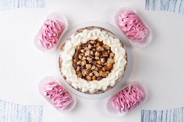 Chocolate puff cake with white cream and nuts on a white box with pink marshmallows