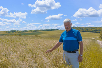 Naklejka na ściany i meble happy old elderly male standing in wheat fields. Healthcare lifestyle senior man walking on field in village.