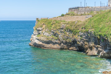 Naklejka premium Stone cliff with sharp protrusions washed by ocean surf