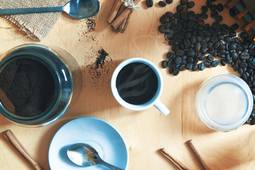 Cup with expresso cafe on a rustic wooden table. Next, some ground coffee and beans with cinnamon....