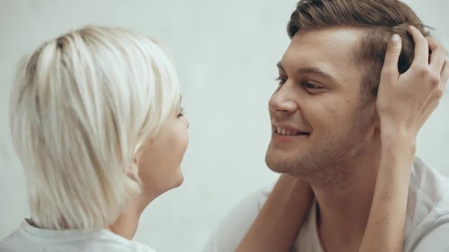 beautiful young couple embracing, smiling and kissing at home