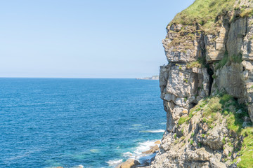 Stone cliff with sharp protrusions washed by ocean surf