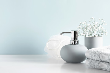 Soft light bathroom decor in pastel blue color, towel, soap dispenser, white flowers, accessories...