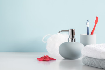 Soft light bathroom decor in pastel blue color, towel, soap dispenser, white flowers, accessories on white wood shelf. Elegant decor bathroom interior.