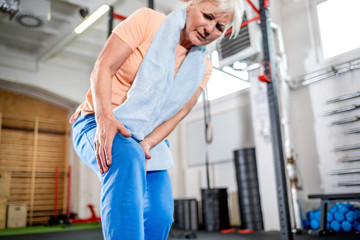 Senior woman at the gym suffering from pain in knee