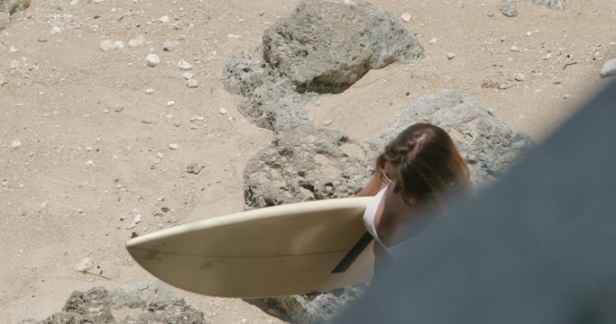 Young modern woman with sexy body in bikini walk the stairs on tropical beach with her short board surf. Tourist urban girl holiday. Summer vacation concept. Internet online freelance work break.
