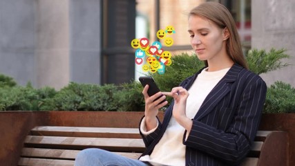 Outdoor Sitting Businesswoman Using Smartphone, Flying Smileys, Emojis and Likes