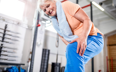 Senior woman at the gym suffering from pain in knee