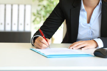 Businesswoman signing a contract on a desktop at office