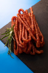 Sausages. Thin sausages with rosemary on a blue background