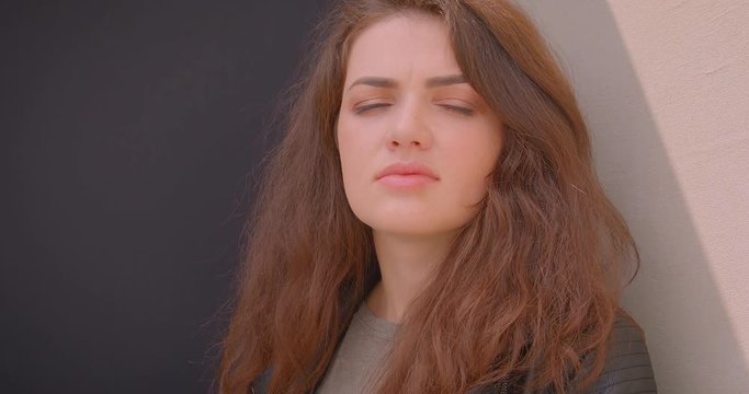 Portrait of serious brunette girl watching into camera being calm and dreamy outdoors on blck and white background.