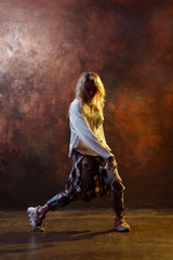 Fototapeta na wymiar Photo of dancing long-haired blonde in torn jeans on brown background