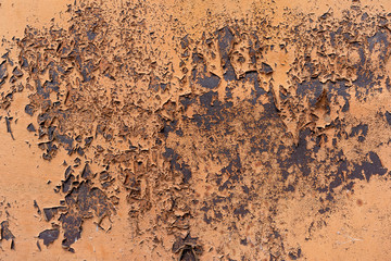 Background peeling red paint on a metal surface. Old painted metal door. Orange Paint is ripped off with metal.