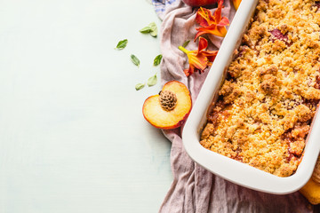 Yummy peach crumble dessert in baking pan on light background , top view. Copy space for your...