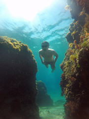 young man dives between rocks in the sea