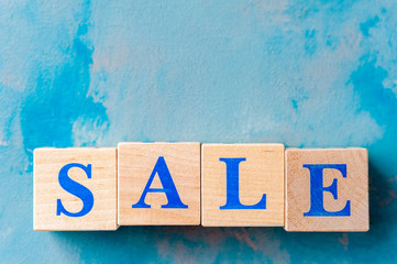 Wooden cubes with word SALE on blue table.