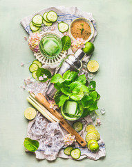 Green refreshing beverage ingredients: lime, cucumber, mint, lemongrass, cane sugar, ice cubes, top view. Summer healthy drinks preparation. Green lemonade. Detox infused water.  Green color . 