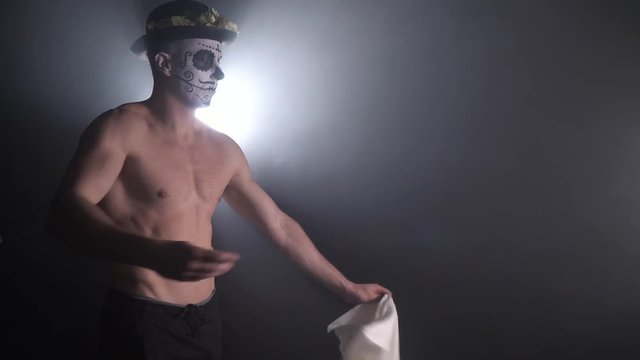 4k footage of a buff man with the mexican face paint taking off his shirt, 4k