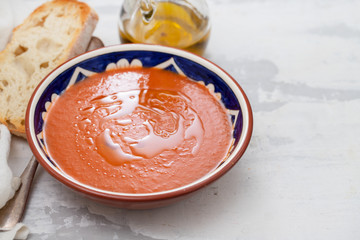 spanish soup gazpacho in bowl with bread and olive oil on ceramic background