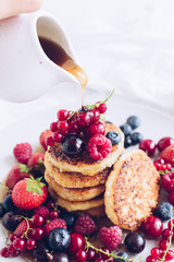 Woman pouring maple syrup on tasty pancakes