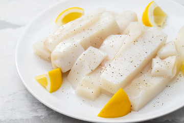 raw squid with pepper and fresh lemon on white plate