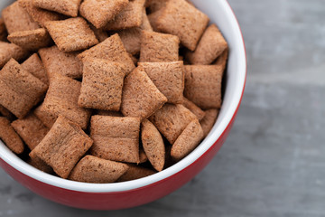 Chocolate pillows in red bowl on ceramic background