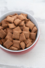 Chocolate pillows in red bowl on ceramic background