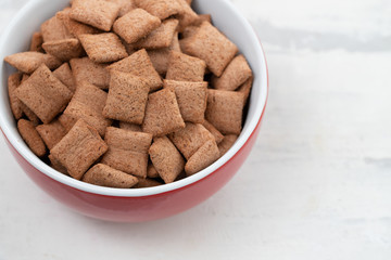 Chocolate pillows in red bowl on ceramic background